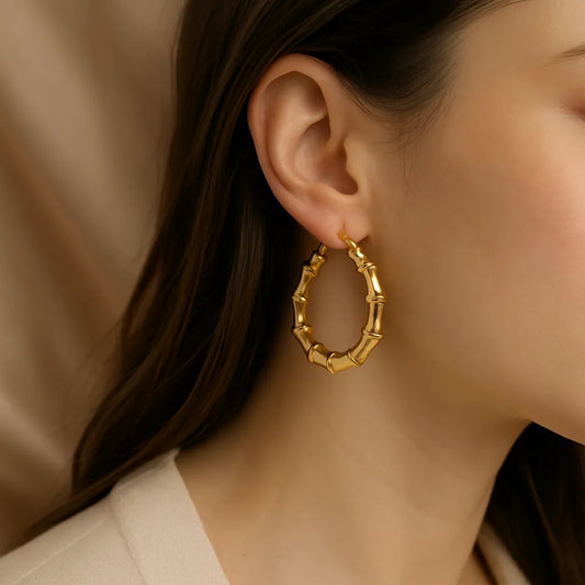 Chunky Bamboo  Gold hoop earring worn by a person with a neutral background
