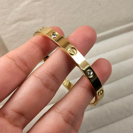 Gold Cartier bracelet by everray with three screws on a neutral background