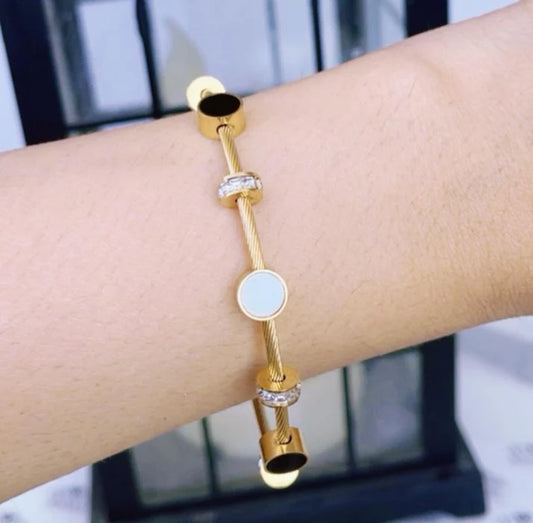 Gold bracelet with circular beads on a wrist against a blurred background