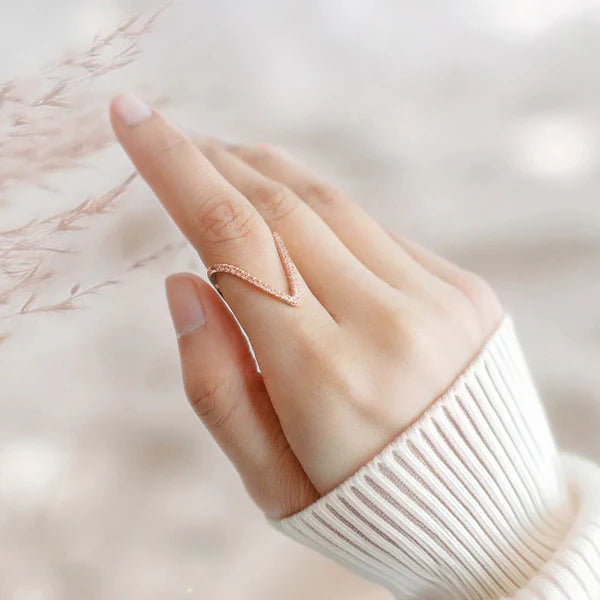 Hand wearing a rose gold ring with a blurred background