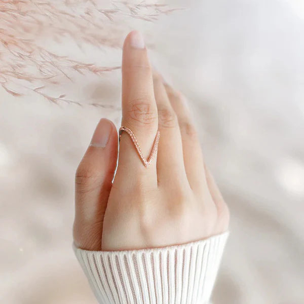 Hand wearing a rose gold ring on a soft, blurred background