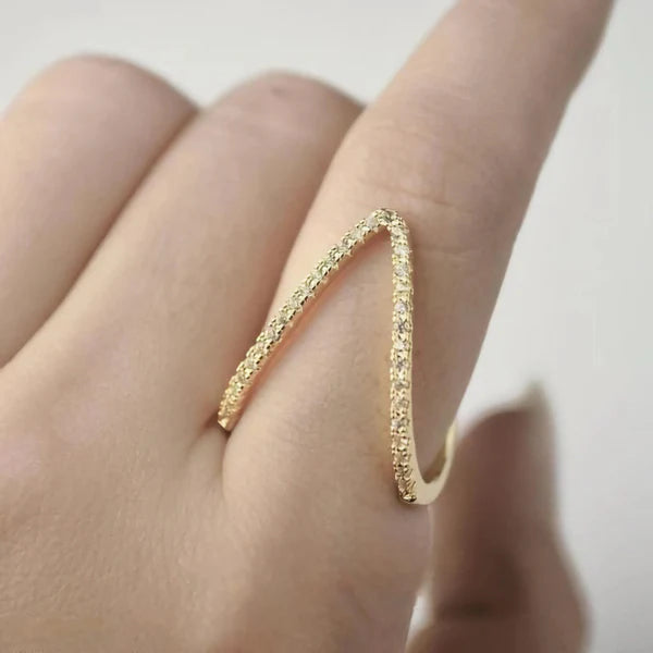 Gold ring on a finger against a neutral background