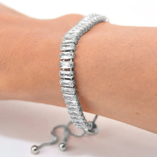 Silver bracelet on a wrist with a plain background
