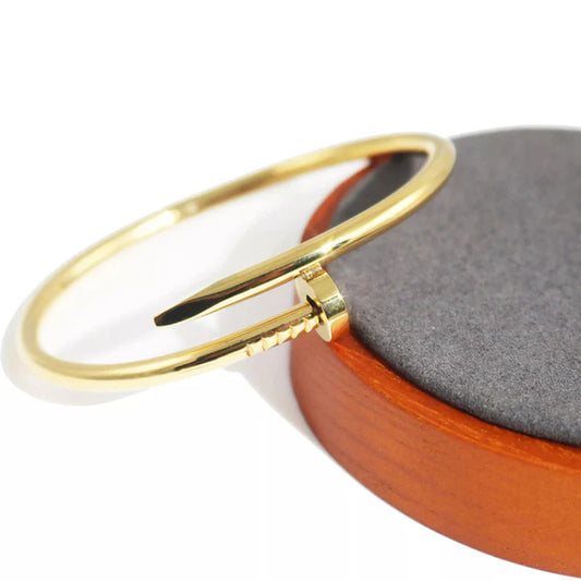 Gold bracelet on a wooden and gray stone surface