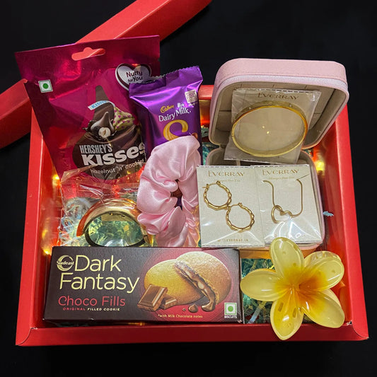 Gift basket with chocolates, jewelry, and a flower on a black background