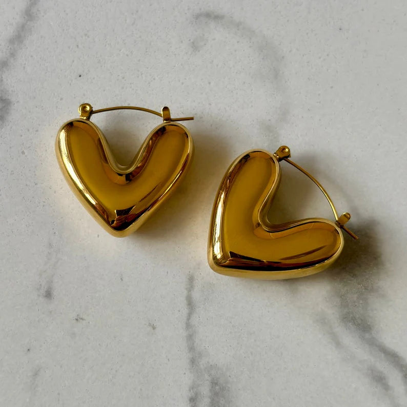Gold heart-shaped hoop earrings on a marble surface