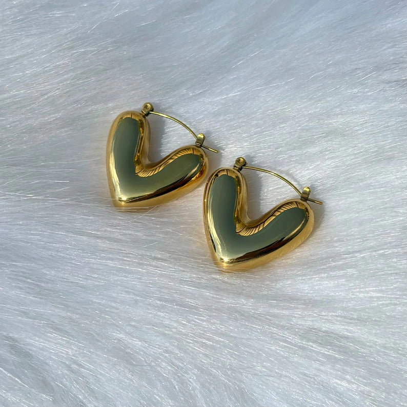 Heart-shaped earrings with gold and green finish on a light gray background