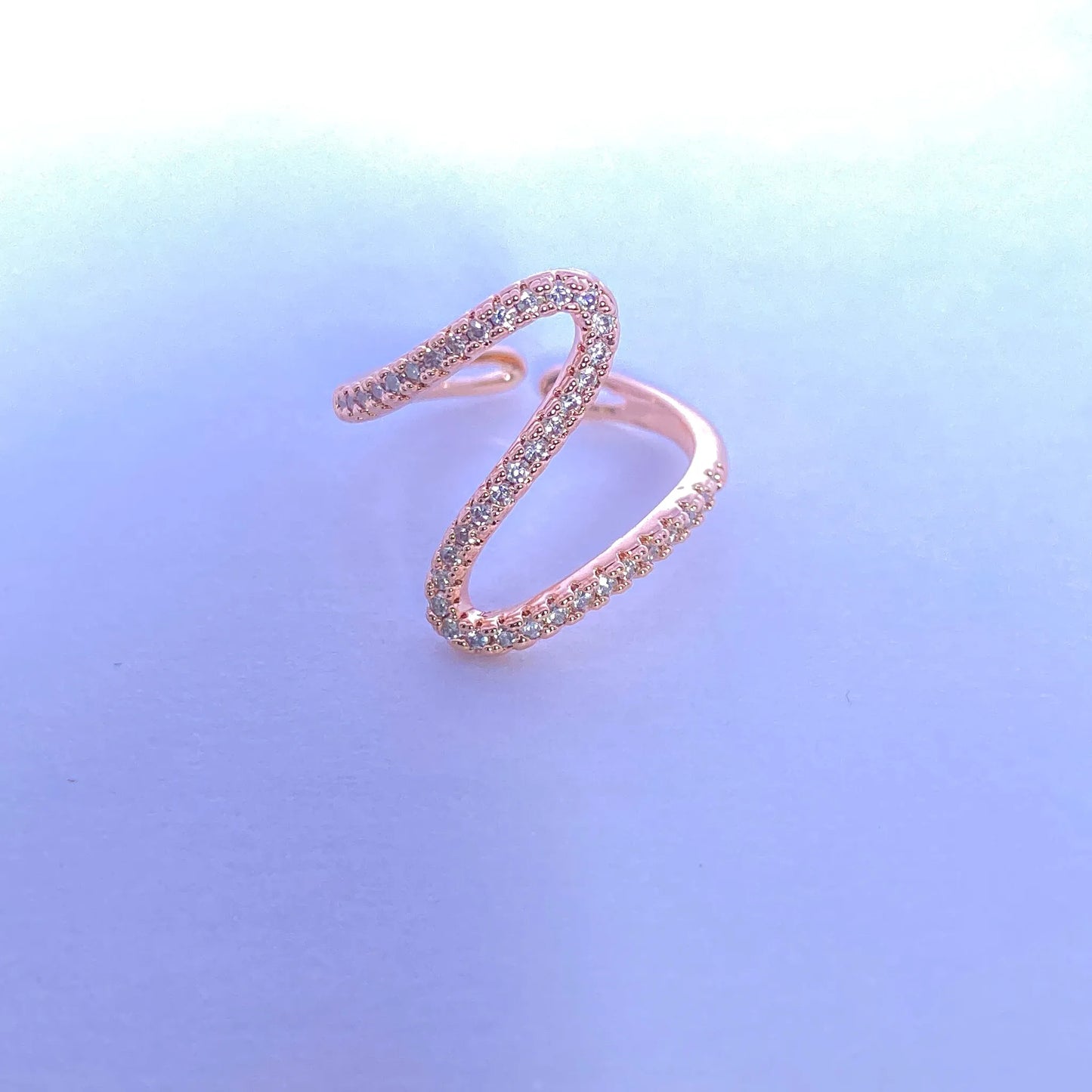 Rose gold ring with gemstones on a gradient blue background