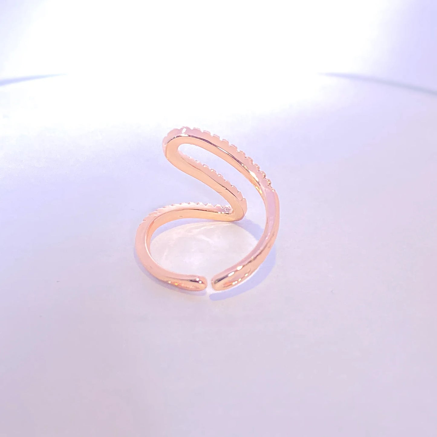 Rose gold ring with small stones on a light purple background