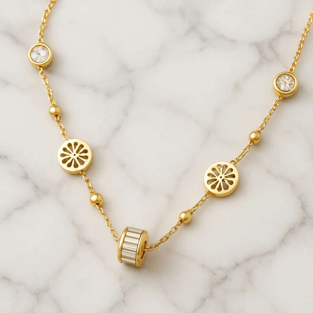 Gold-toned necklace featuring lotus-inspired medallions, bezel-set crystals, and a center baguette charm on adjustable chain.