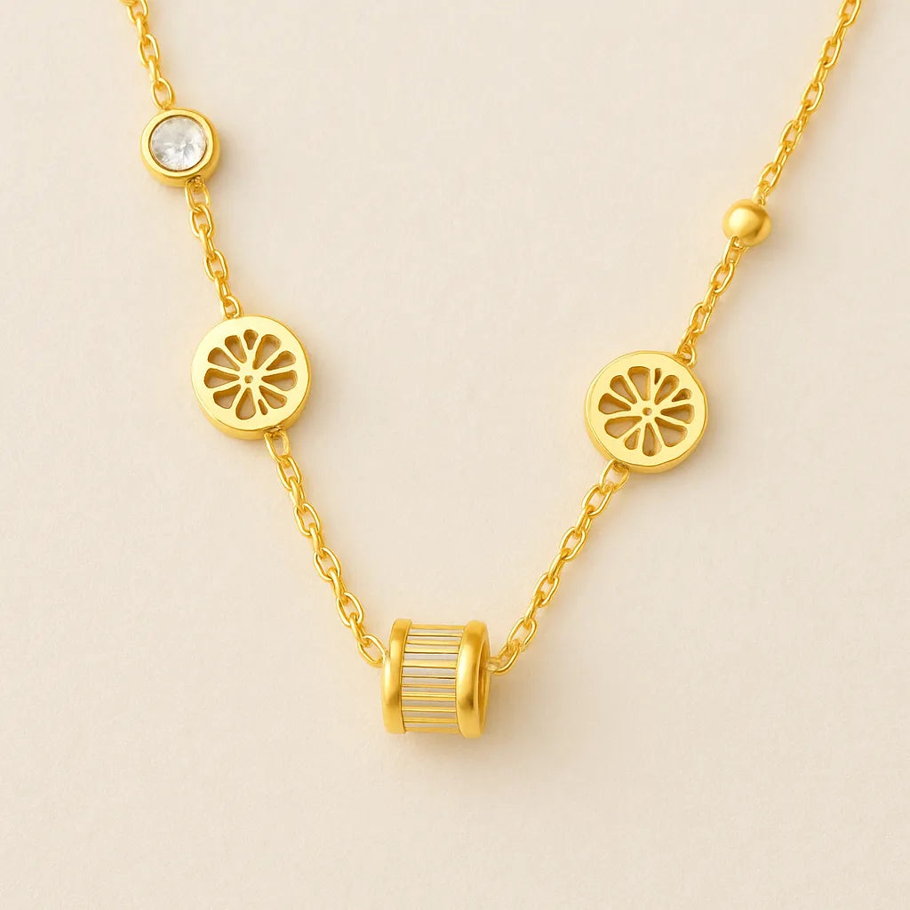 Gold-toned necklace featuring lotus-inspired medallions, bezel-set crystals, and a center baguette charm on adjustable chain.
