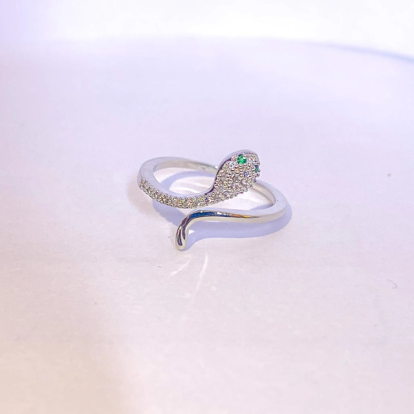 Silver ring with green gemstone on a light gradient background