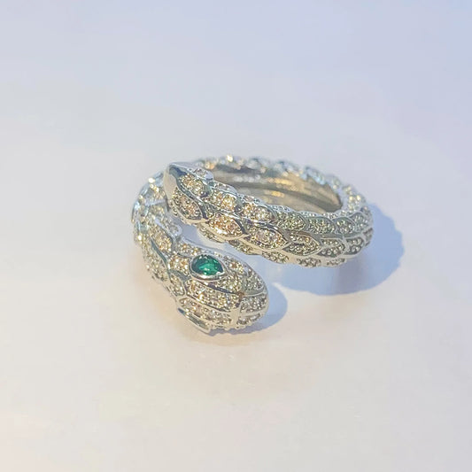 Silver snake-shaped ring with a green gemstone on a light gray background