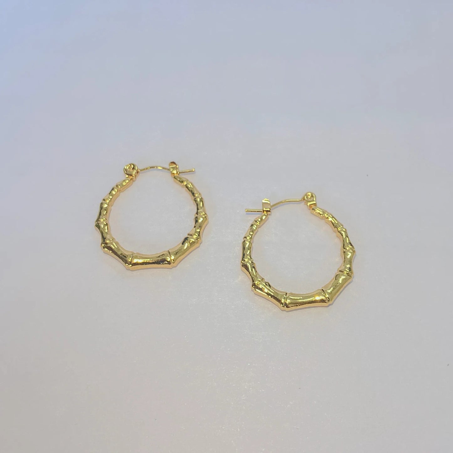 Gold hoop earrings on a light gray background