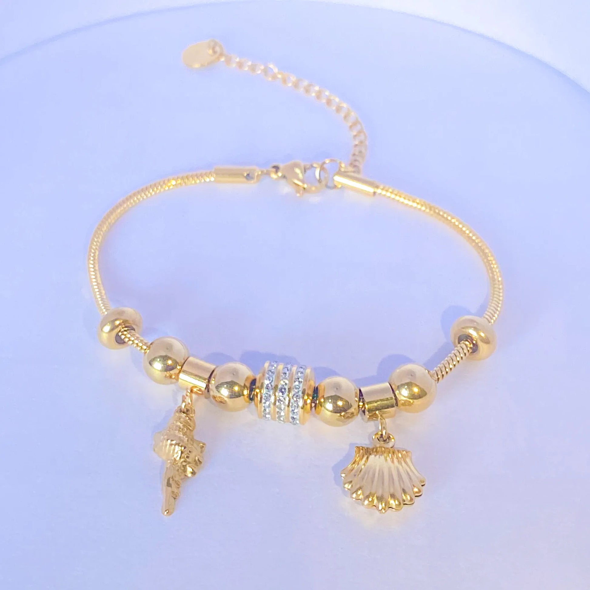 Bold coral Charm Summer Bracelet  by everray with shell and conch shell charms on a light blue background
