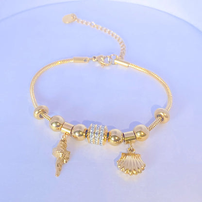 Bold coral Charm Summer Bracelet  by everray with shell and conch shell charms on a light blue background