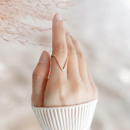 Hand wearing a rose gold ring on a soft, blurred background