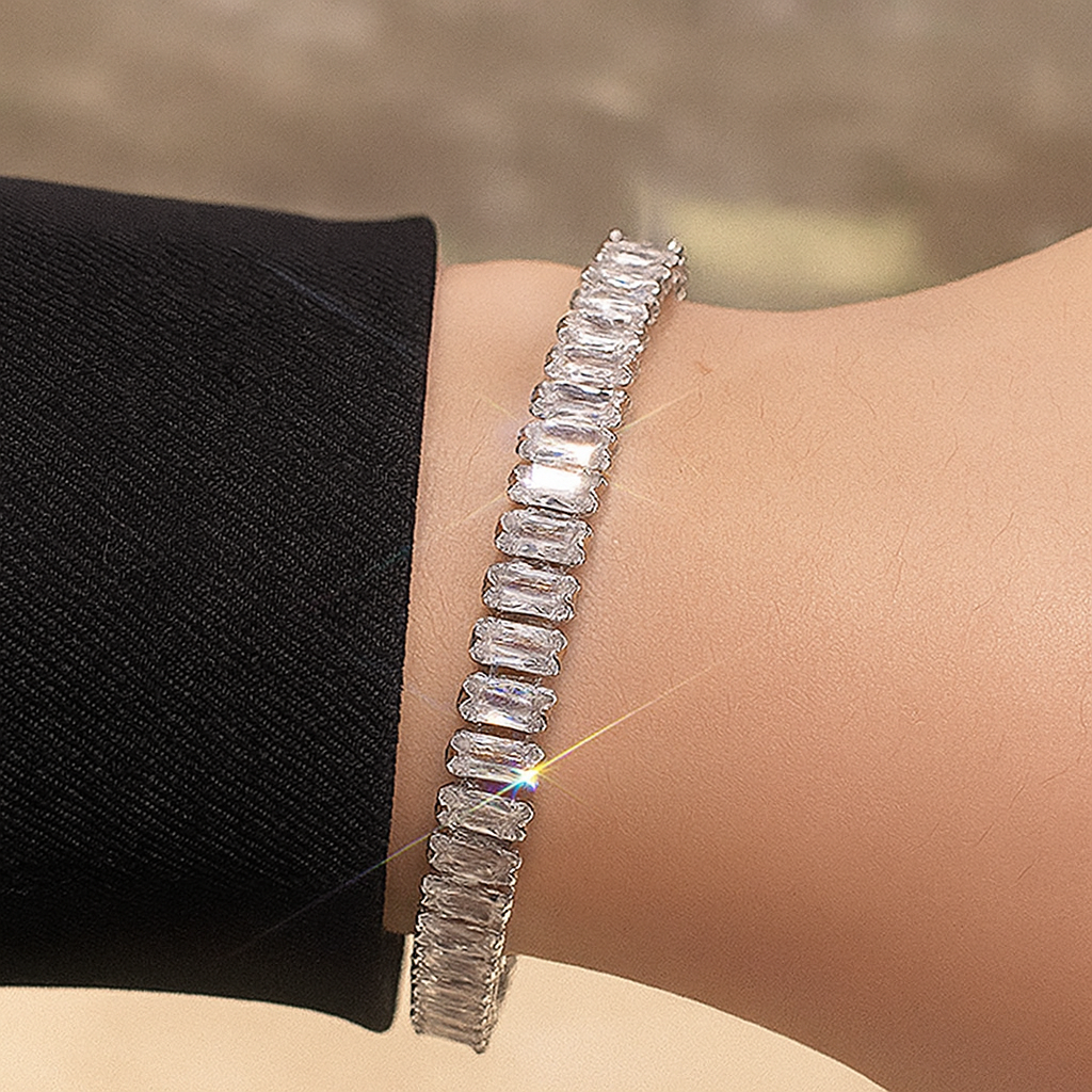 Silver bracelet with baguette-cut diamonds on a wrist against a neutral background