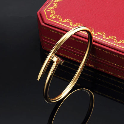 Gold bracelet on a dark surface with a red box featuring gold text in the background