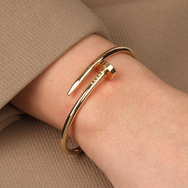 Gold bangle on a wrist with a neutral background