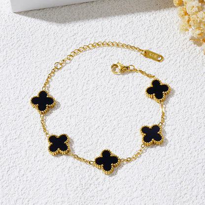 Gold bracelet with black clover-shaped charms on a white background