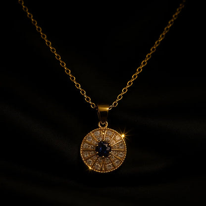 Gold evil eye pendant necklace with blue and white crystals in a circular chakra-style design on gold chain.