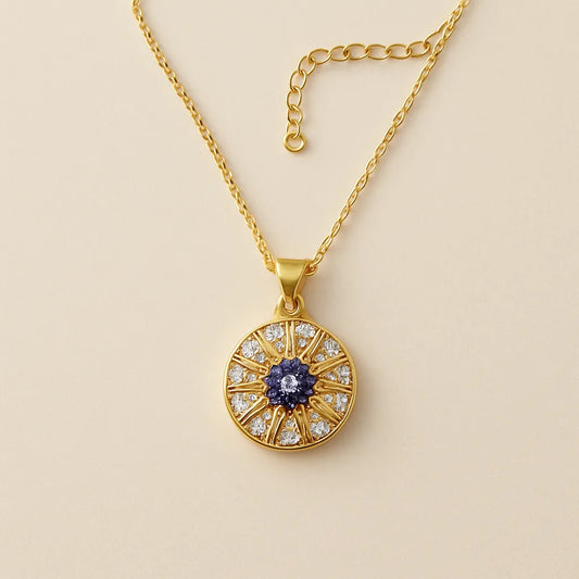 Gold evil eye pendant necklace with blue and white crystals in a circular chakra-style design on gold chain.