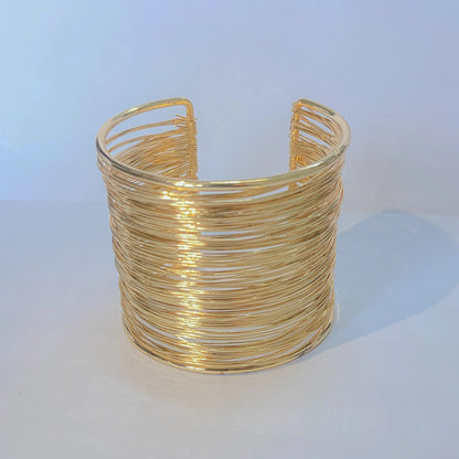 Gold wire cuff bracelet on a white background