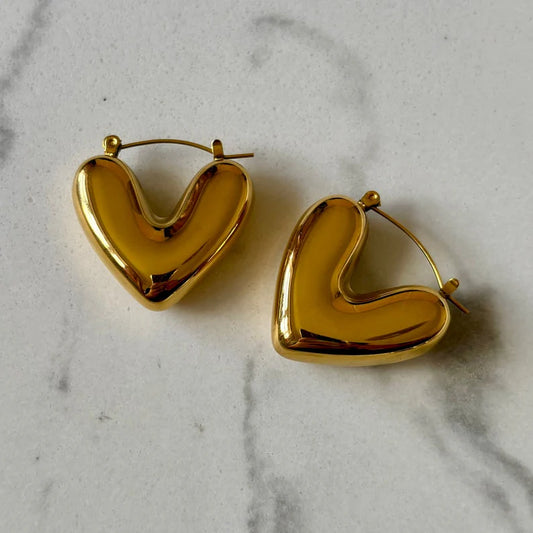 Gold heart-shaped hoop earrings on a marble surface