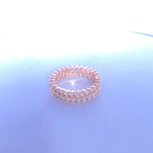 Rose gold ring with clear stones on a gradient blue background