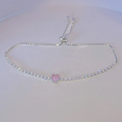 tesnnis bracelet with a heart-shaped pink gem on a white background
