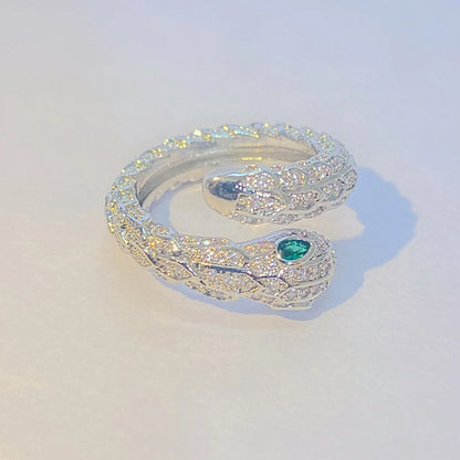Silver snake-shaped ring with a green gemstone on a light gray background