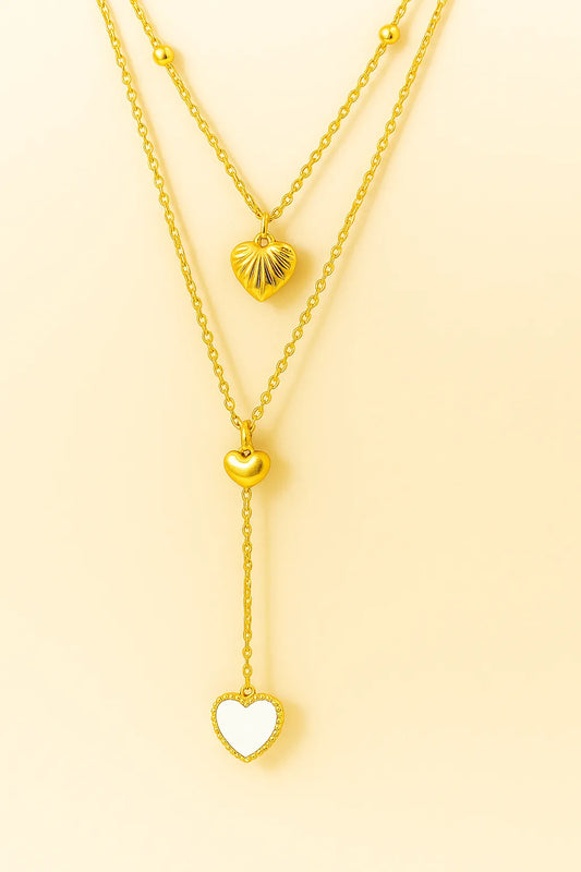 Two gold necklaces with heart pendants on a yellow background